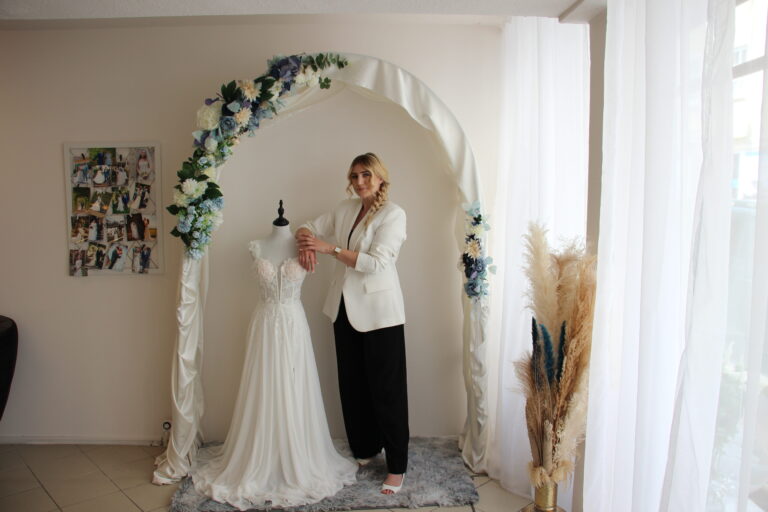Besitzerin Caro steht in ihrem Atelier "la vie en rose" neben einem Brautkleid auf einer Schneiderpuppe und blickt in die Kamera.