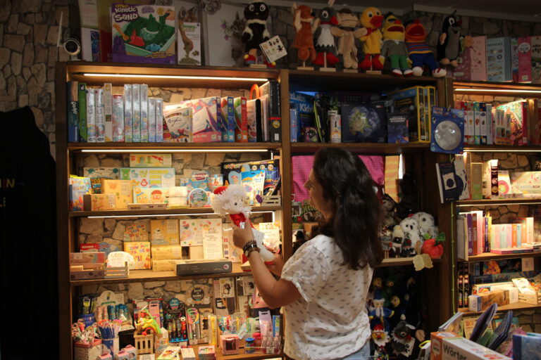 Kundin betrachtet Regale mit Spielzeug, Büchern und Spielen im Spielschlau Jena