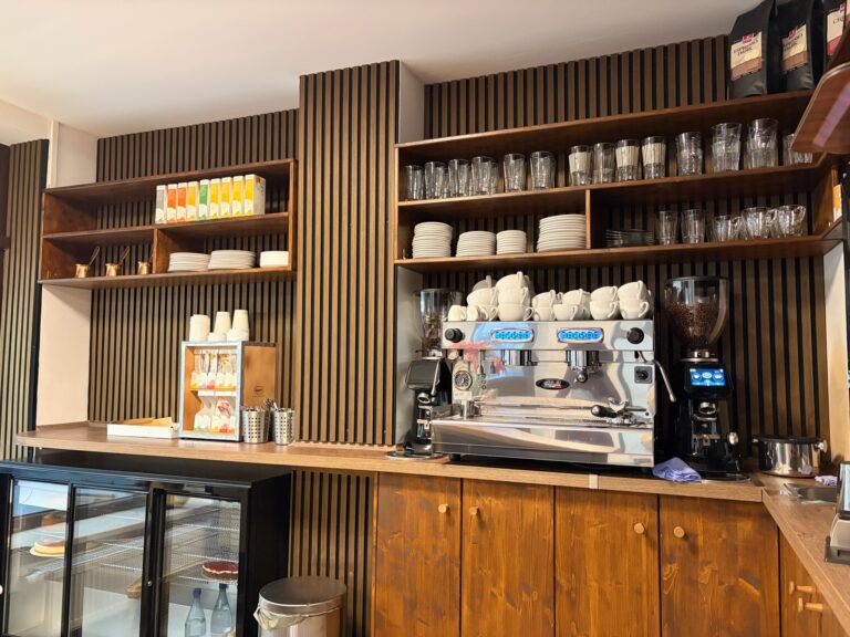 Thekenbereich der Koriat Kuchenmanufaktur mit hochwertiger Espressomaschine, Bohnenmühle und Holzeinrichtung.