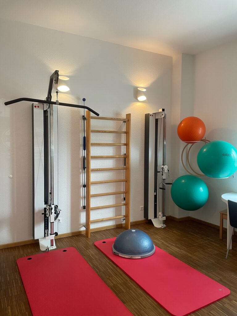 Trainingsmatten, Gymnastikbälle, eine Sprossenwand und weitere Trainingsgeräte befinden sich in einem Therapieraum.