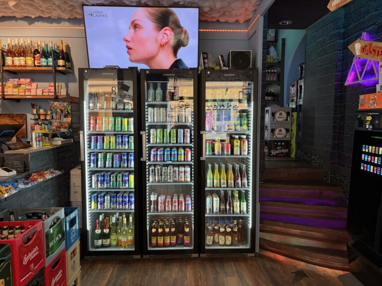 Drei große, beleuchtete Kühlschränke voll gefüllt mit Bier, Limonaden und Mate-Getränken in der Trinkstube Jena.
