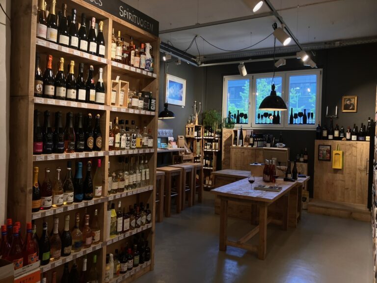 Großes Holzregal, gefüllt mit verschiedenen Spirituosen wie Gin und Likören sowie ausgewählten Weinen.