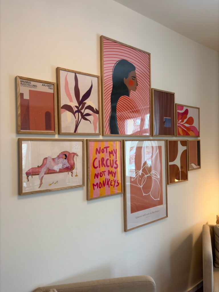 Eine Zusammenstellung von elf verschiedenen Kunstdrucken in Holzrahmen an einer weißen Wand. Die Motive variieren zwischen abstrakten Formen, Pflanzen und Typografie ("Not my circus, not my monkeys").