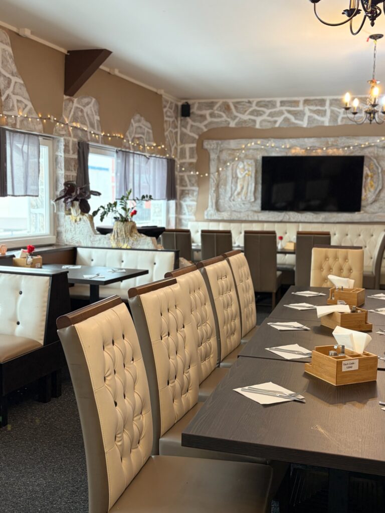 Sitzbereich im Restaurant mit gepolsterten Sitzbänken an einem langen und gedeckten Tisch in warmem Licht.