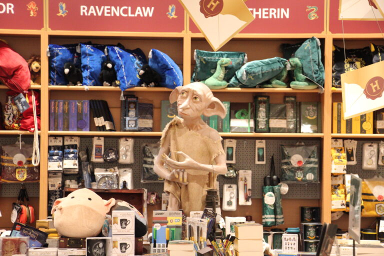 Große Harry-Potter-Themenwelt im Laden mit schwebenden Briefen an der Decke, den Wappen der Häuser und einer Dobby-Figur.