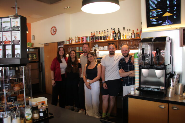 Das sechsköpfige Team von The Bean steht gut gelaunt für ein Gruppenfoto hinter der Theke.