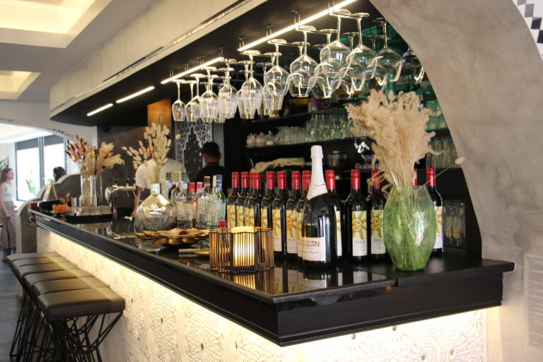 Die schwarze, beleuchtete Bar im Naan n Curry mit hängenden Weingläsern, Spirituosen und Dekoration.