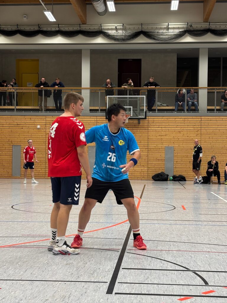 Nahaufnahme eines Zweikampfs zwischen einem HBV-Spieler im blauen Trikot und einem gegnerischen Spieler im roten Trikot.