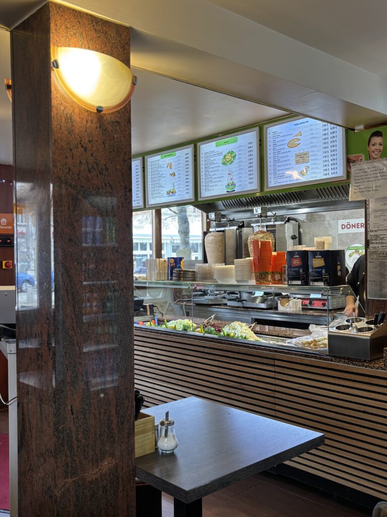 Blick in den Gastraum von Dürüm Point Jena auf den Verkaufstresen, die Menütafeln und die Döner-Spieße.