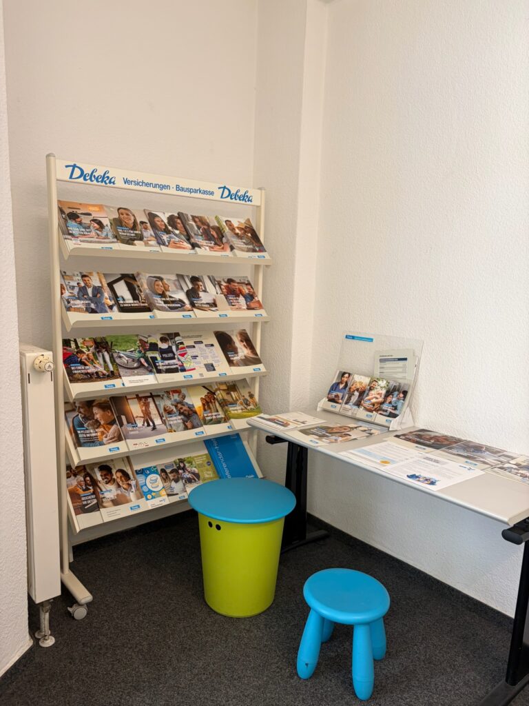 Wartebereich im Debeka-Büro mit Infomaterial und einer kleinen Kinderecke mit bunten Hockern und Maltisch.