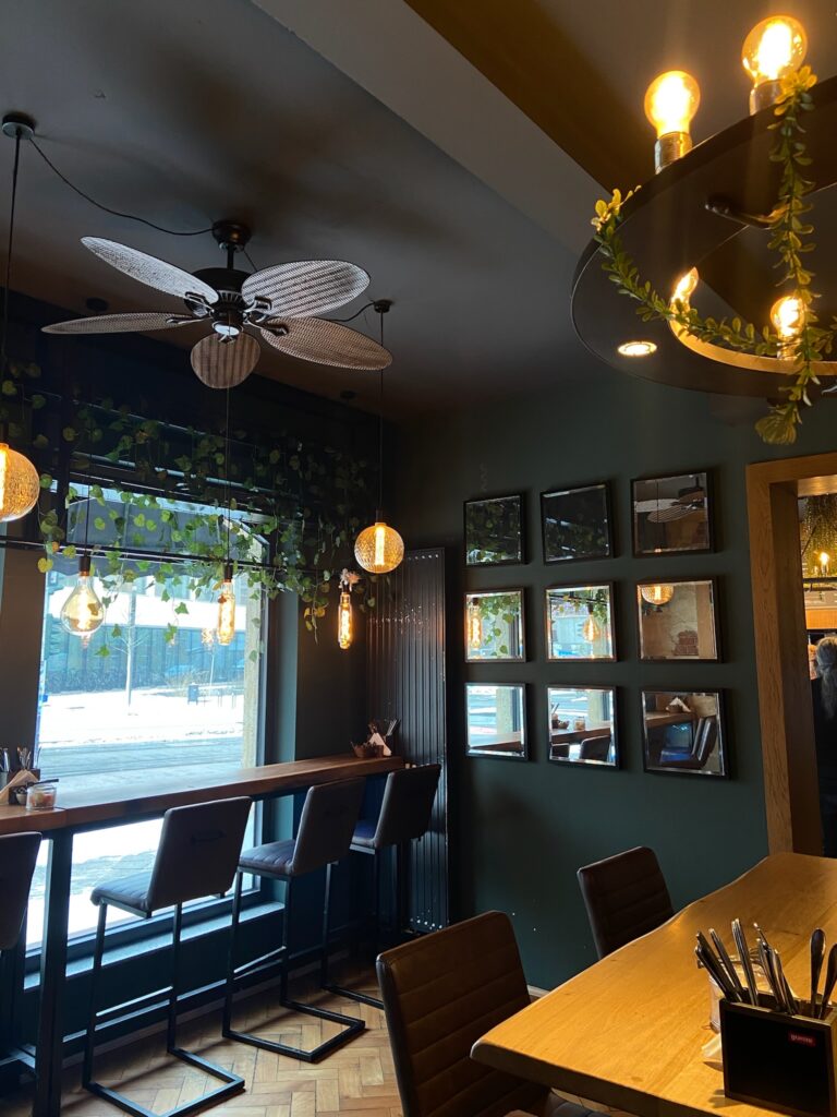 Hohe Barhocker an einem langen Holztisch direkt am großen Fenster mit Blick auf eine verschneite Straße in Jena.