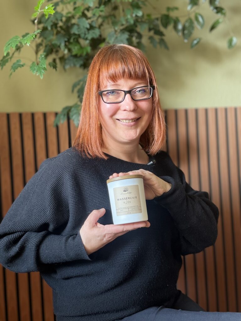 Stephanie Böhner, die Gründerin von Himmlitz Kerzen, sitzt und hält eine weiße Kerze in ihren Händen, die sie selbst hergestellt hat.