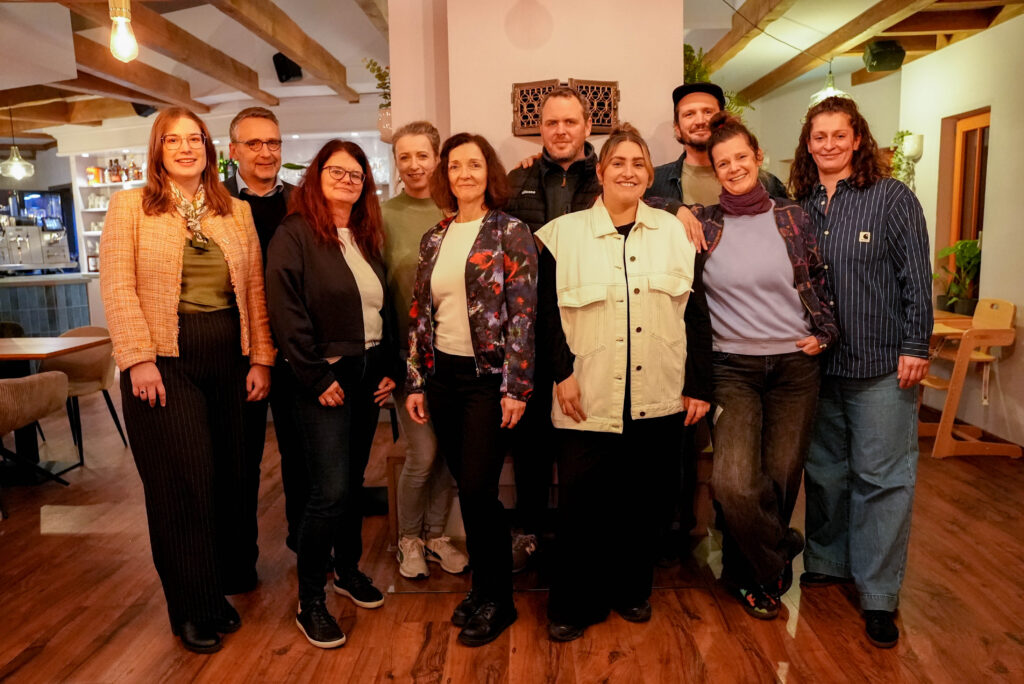 Gruppenfoto von Vorstand und Mitarbeitenden der Initiative Innenstadt Jena e.V., aufgenommen in einem warm beleuchteten Innenraum