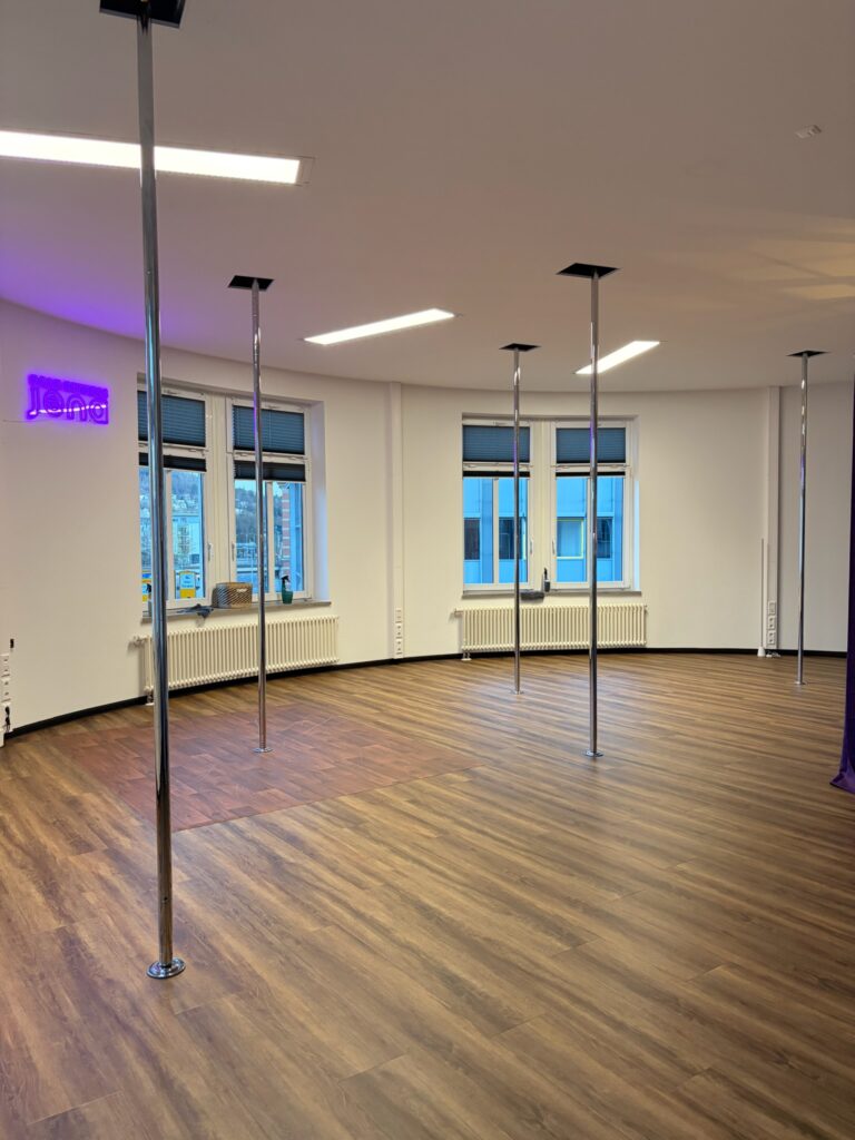 Großer Raum mit mehreren Pole-Stangen und Holzboden