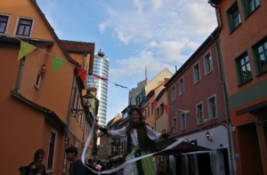 Straßenkünstlerin auf Stelzen beim Wagnergassenfest 2025 in einer bunt geschmückten Gasse der Jenaer Innenstadt