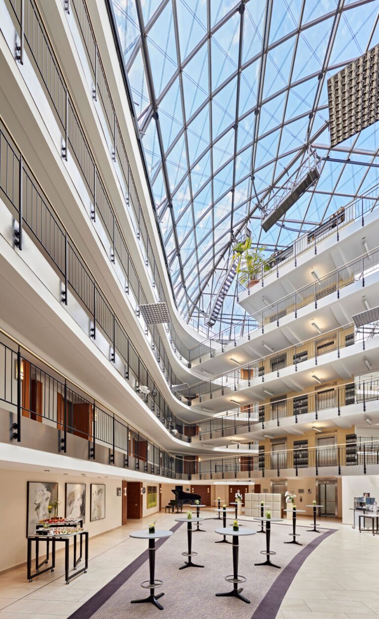 Helles Atrium des Dorint Hotel Esplanade Jena mit Glasdach und mehreren offenen Etagen.