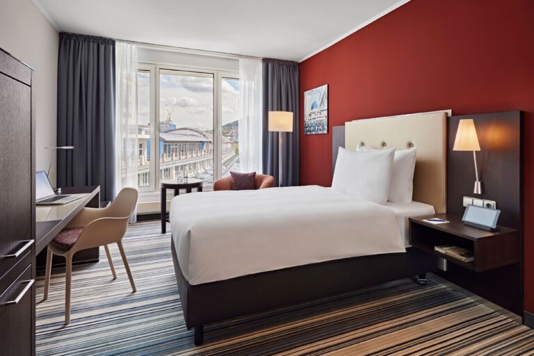 Modernes Hotelzimmer im Dorint Hotel Esplanade Jena mit Bett, Schreibtisch und großem Fenster.