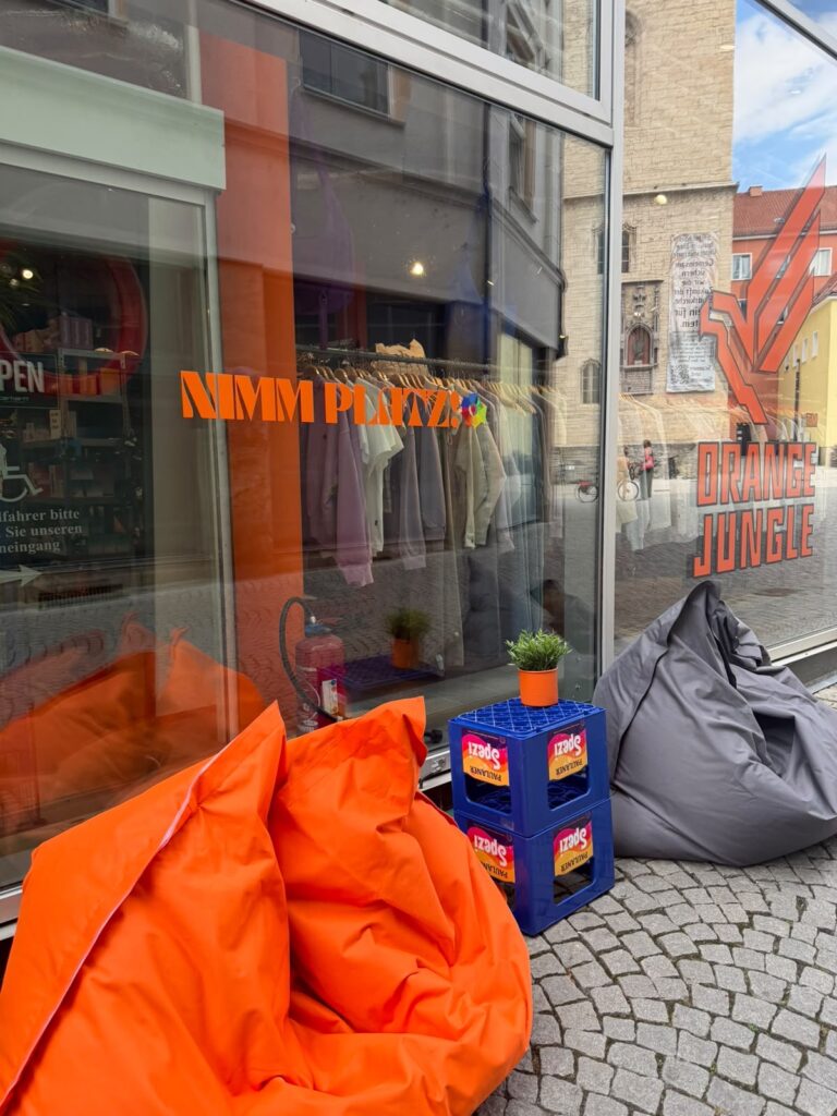 Orangefarbene und graue Sitzsäcke mit kleiner Ablage vor dem Schaufenster von Orange Jungle in Jena
